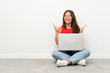 © luismolinero - Young woman with a laptop sitting on the floor laughing