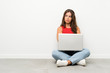 © luismolinero - Young woman with a laptop sitting on the floor thinking an idea
