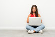 © luismolinero - Young woman with a laptop sitting on the floor pleading