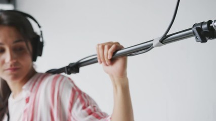 Wall Mural - Female Sound Recordist Holding Microphone On Video Film Production In White Studio