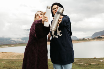 Lifestyle portrait of two best friends, smiling and having fun together. Outdoor photo of two young women, one with hijab, enjoying each other company and drinking coffee.