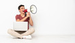 © luismolinero - Teenager man sitting on the flor with his laptop shouting through a megaphone
