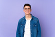 © luismolinero - Teenager caucasian  handsome man isolated on purple background with glasses and happy