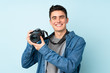© luismolinero - Teenager photographer man isolated on blue background