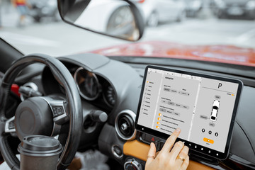 Woman controlling car with a digital dashboard switching autopilot mode, close-up on a touchscreen with launched program. Smart electric car concept