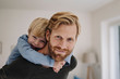 © Westend61 - Portrait of smiling father carrying son piggyback at home