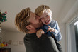 © Westend61 - Father carrying and kissing son at home
