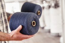 Close-up Of Man Holding Cotton Reels In A Textile Factory