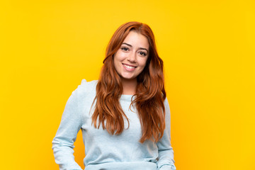 Wall Mural - teenager redhead girl over isolated yellow background laughing