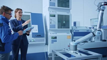 Aufkleber - Modern Factory: Female Project Manager and Male Engineer Standing, Talking and Using Tablet Computer for Programming Robot Arm Assembly Line. Industry 4.0 Facility with High Tech CNC Machinery
