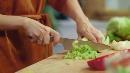 Wall Mural - Woman hands chopping celery on cutting board. Housewife cooking fresh vegetables