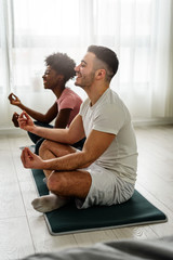 Young smiling multi ethnic couple exercising together at home