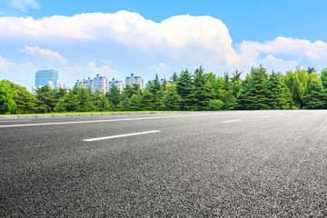 Empty asphalt road and green forest under blue sky.