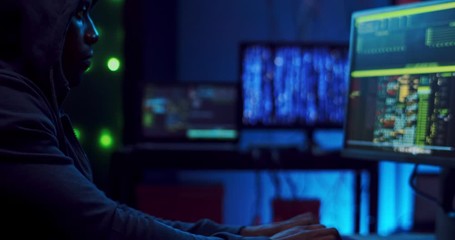 Close up of the African American young male hacker or software developer tapping, typing and texting on the keyboard of computer at night while programming.hacker concept