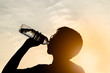 © sattawat - Close up Silhouette young Asian man wearing glasses is drinking water after work out in evening
