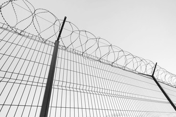 Slatted fence with barbed wire on top.