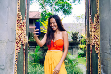 Smiling Asian woman taking selfie in tropical garden