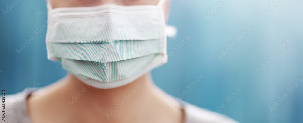 young woman in medical face protection mask indoors on blue background - obrazy, fototapety, plakaty 