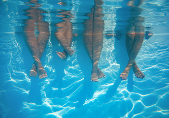 Wall Mural - close up of friends, family legs underwater in the swimming pool with copy space
