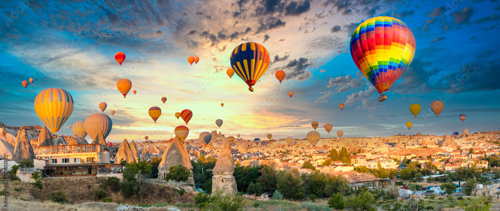 Colorful hot air balloons flying over at fairy chimneys in Nevsehir, Goreme, Cappadocia Turkey. Hot air balloon flight at spectacular Cappadocia Turkey. - obrazy, fototapety, plakaty 