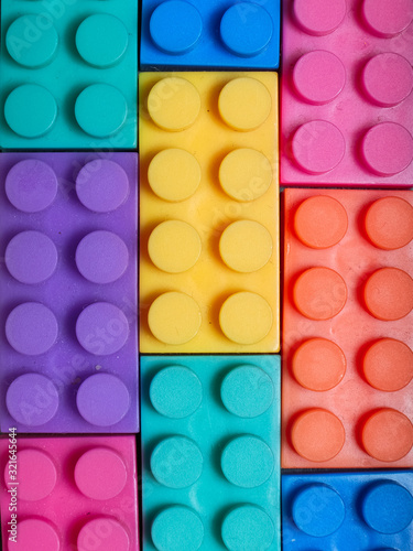 Multiple colored plastic building blocks on a gray textured background © Dusko