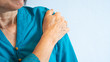An old woman in blue blouse getting shoulder pain, white background