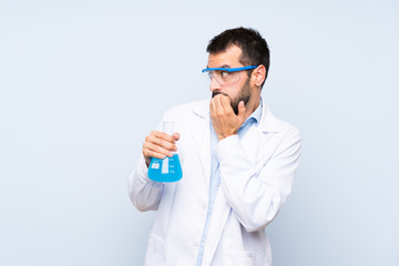 Wall Mural - Young scientific holding laboratory flask over isolated background nervous and scared putting hands to mouth