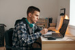 © Alena Ozerova - Teenage boy doing homework using computer sitting by desk in room alone