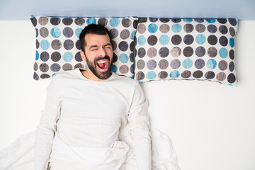 Man in bed in top view shouting to the front with mouth wide open