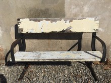Old Shabby Worn Wooden Dilapidated Park Bench With Metal Legs Against A Stone Wall. White Paint Chips.
