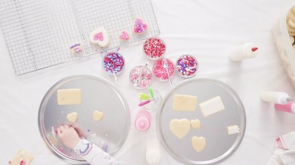 Poster - Flat lay. Step by step. Little girl decorating decorating sugar cookies with royal icing and sprinkles for Valentine's Day.