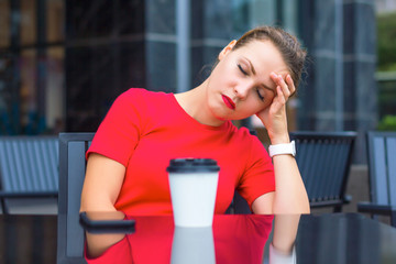 Tired exhausted girl, young beautiful woman sleeping in a cafe outdoors with a cup of coffee. Deadline, overworked and sleep deprivation, monday morning concept. Take a nap, snooze. Headache, migraine