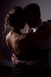 © Denis Ivanov - Passionate couple: a woman with a blonde hairdo wearing a black dress and a handsome unshaven man in a suit pose in a dark Studio