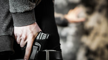 Man Holding Out Hand While Drawing A Concealed Pistol. Personal Protection Concept