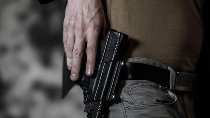 Man reaching for a pistol on his belt. Open carry and second amendment concept.