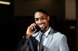© Carlos David - Close up portrait of a happy smiling young man in business suit holding cell phone, talking and looking at camera