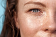 Summer Freestyle. Young woman with freckles standing isolated on blue eye close-up looking camera excited