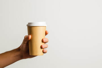 Mockup of male hand holding a Coffee paper cup isolated on light grey background