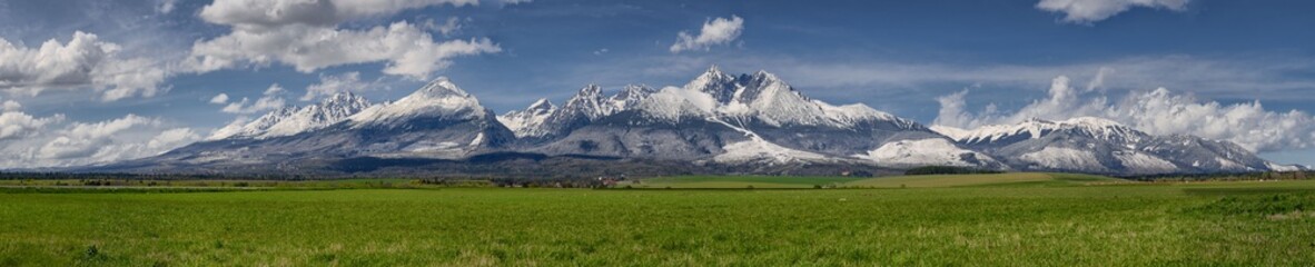 Extra wide panorama of High Tatra main ridge of mountains during April with snowy hills and blue sky with clouds, Vysoke Tatry, Slovakia