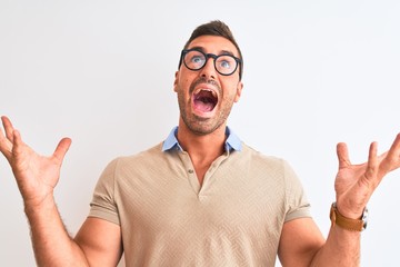 Wall Mural - Young handsome man wearing glasses over isolated background celebrating crazy and amazed for success with arms raised and open eyes screaming excited. Winner concept