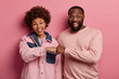 © wayhome.studio  - Cheerful ethnic friends make fist bump, agree to work in team, smile broadly, wears pink pastel clothes, have good mood, rejoice complete deal or well done job, isolated on rosy studio wall.