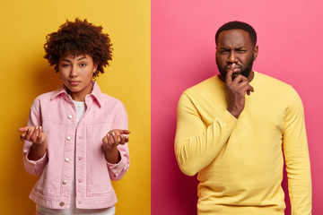 Photo of hesitant dark skinned woman shrugs shoulders, poses unaware, thoughtful black man tries to decide something, make future plannings, isolated on yellow and pink background. Indignant couple