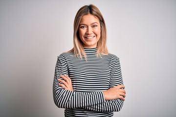 Young beautiful blonde woman wearing casual striped sweater over isolated background happy face smiling with crossed arms looking at the camera. Positive person.