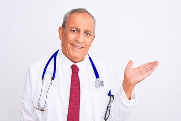 Sticker - Senior grey-haired doctor man wearing stethoscope standing over isolated white background smiling cheerful presenting and pointing with palm of hand looking at the camera.