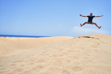 Wall Mural - Young handsome man jumping at the beach