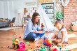 © Krakenimages.com - Caucasian girl kid playing and learning at playschool with female teacher. Mother and daughter at playroom around toys playing with bulding blocks