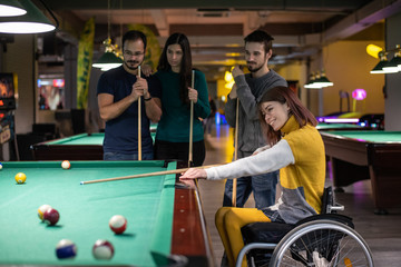 Disabled woman in a wheelchair playing billiards with friends