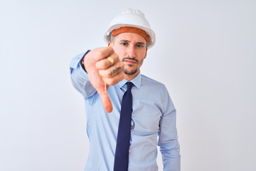 Poster - Young business man wearing contractor safety helmet over isolated background looking unhappy and angry showing rejection and negative with thumbs down gesture. Bad expression.