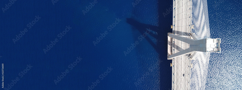 Aerial drone ultra wide photo of suspension cable bridge over deep blue sea - obrazy, fototapety, plakaty 