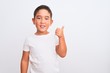 © Krakenimages.com - Beautiful kid boy wearing casual t-shirt standing over isolated white background doing happy thumbs up gesture with hand. Approving expression looking at the camera showing success.